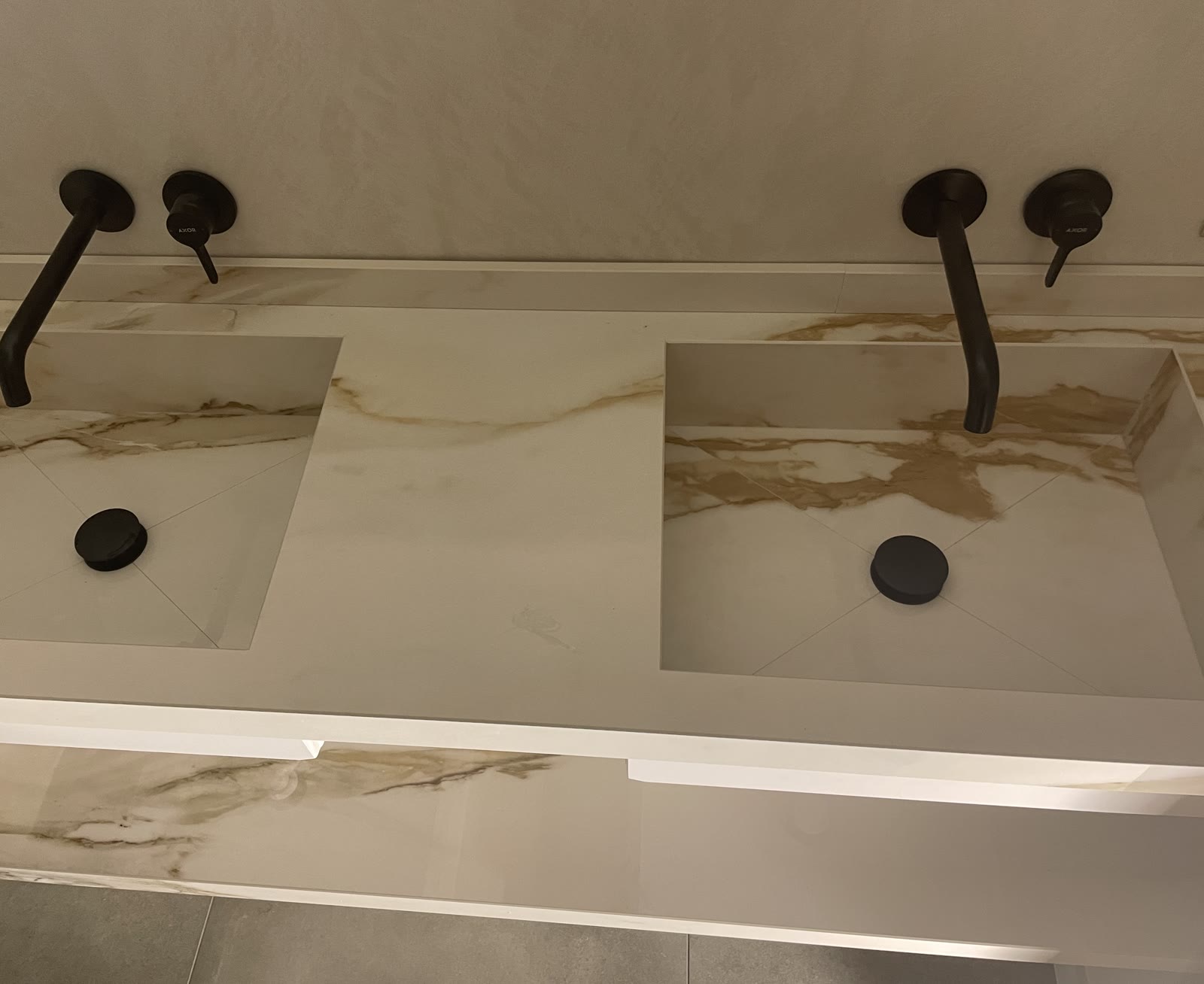 Dubbele wastafel uitgesneden in marmer, met matzwarte Axor-kranen